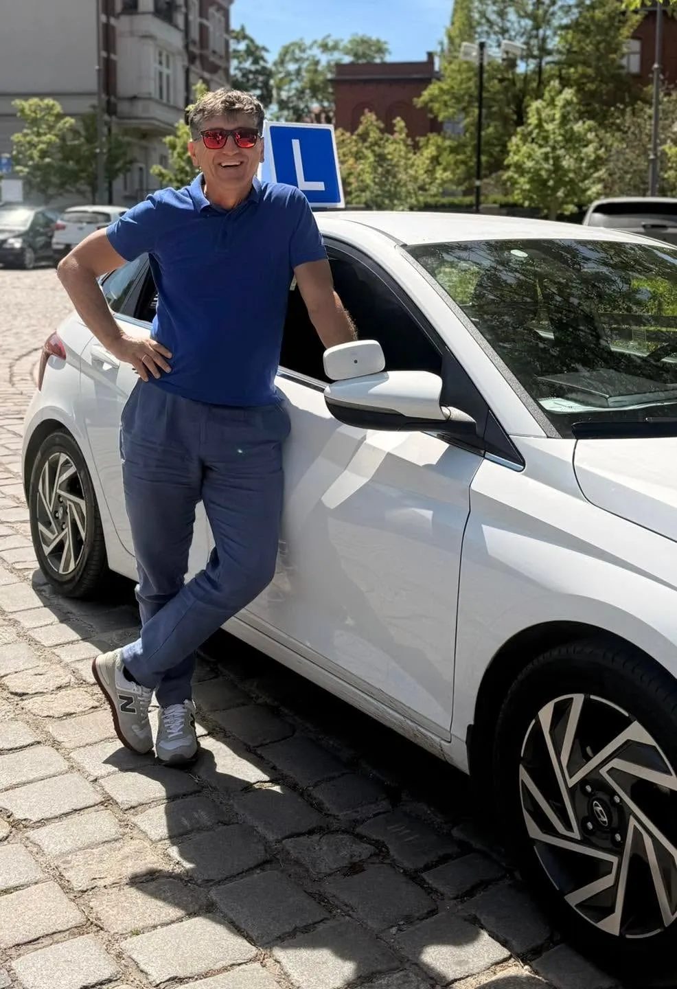 Piotr Stokłosa oparty o szkolnego Hyundaia i20 z tablicą L, na ulicy w Wałbrzychu