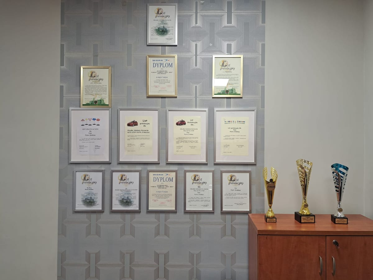 Ściana w biurze Auto-Stop obwieszona dyplomami i listami gratulacyjnymi w ramkach